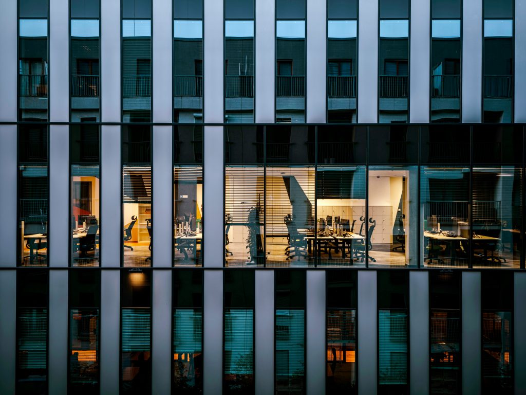 Empty desks visible through office windows at dusk